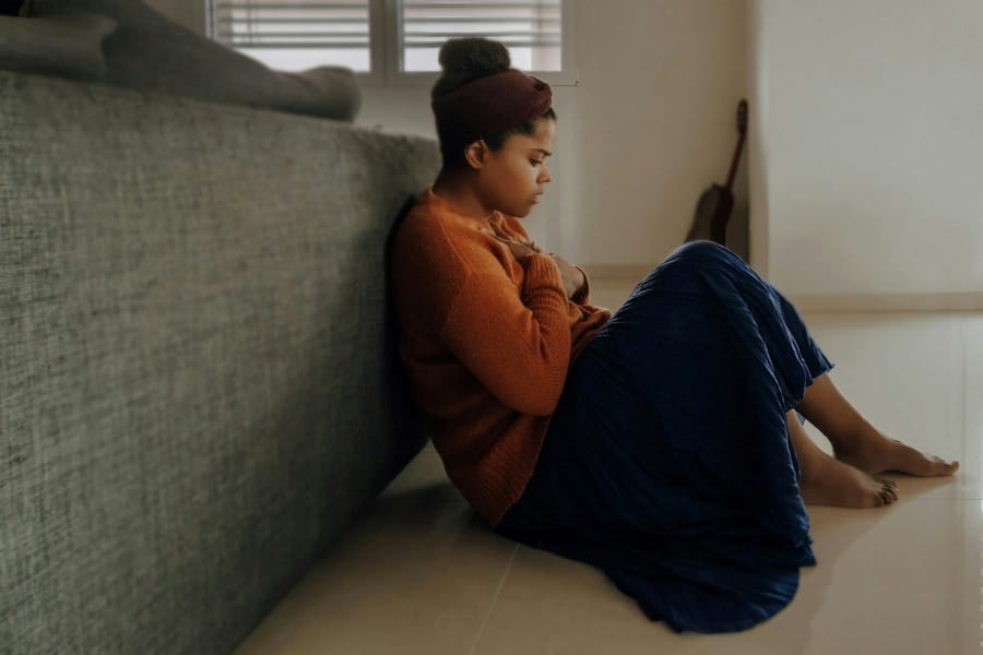 woman in orange sleeve shirt sitting near gray couch
